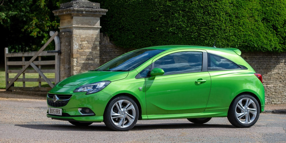 Green Vauxhall Corsa parked in front of gates