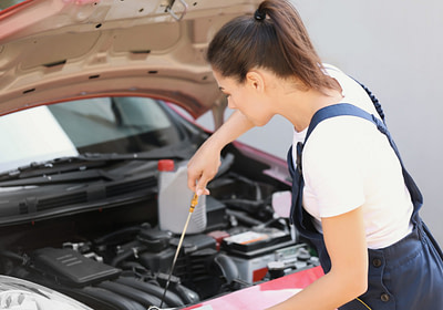 woman removing parts from engine preparing for selling your car for parts
